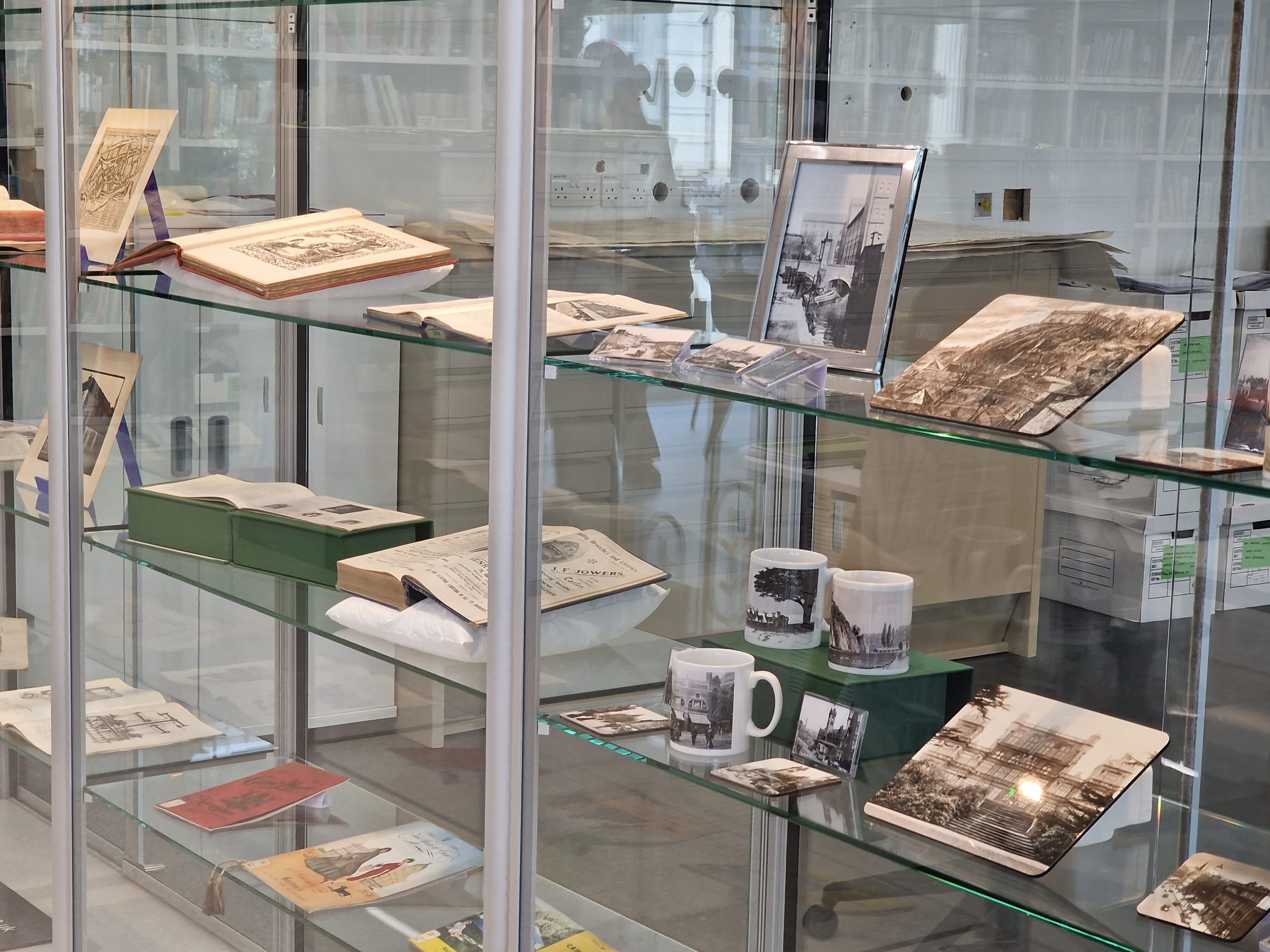 A series of historic books and maps are on display in an exhibition area scaled